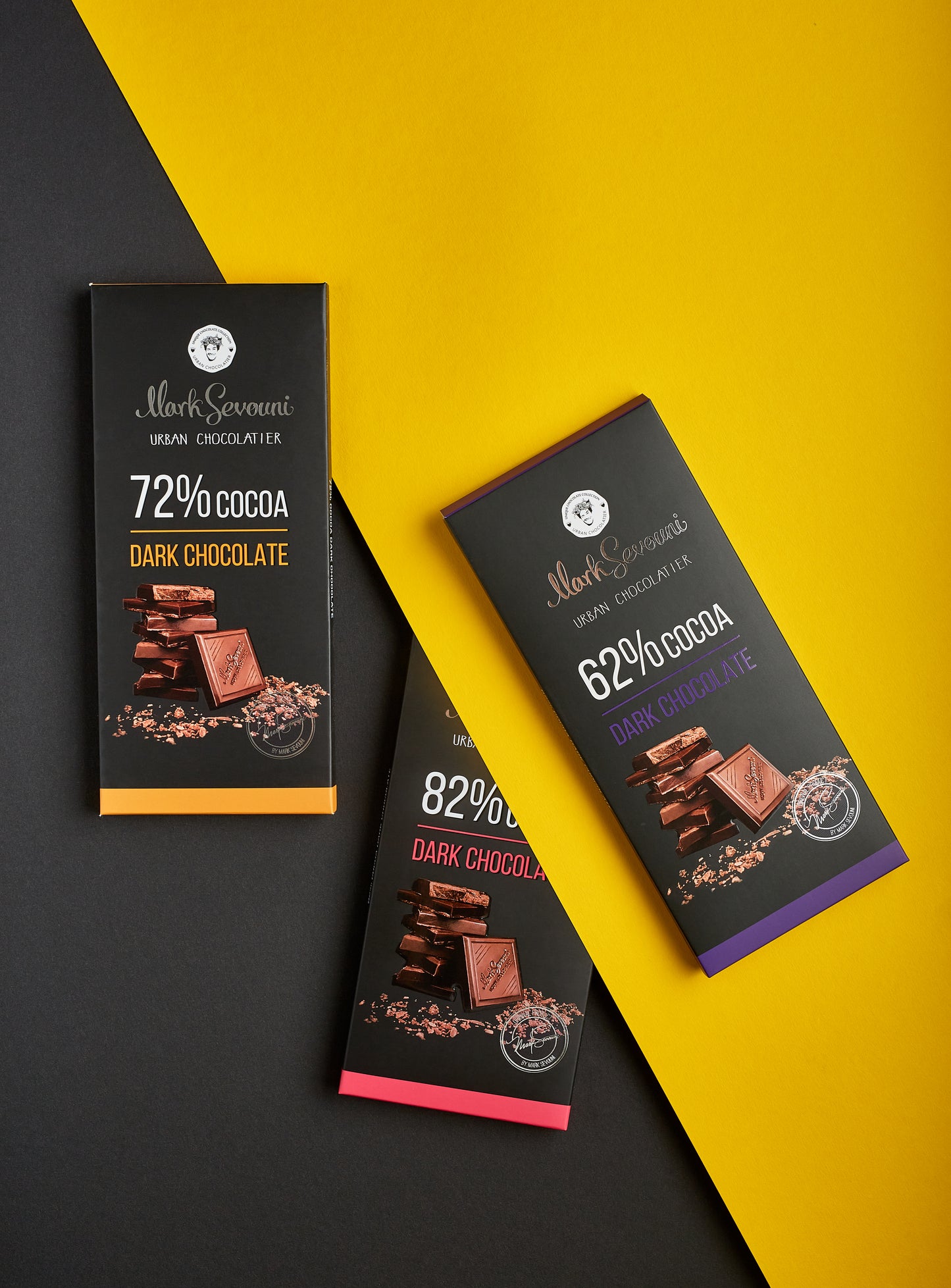Trio of Mark Sevouni Urban Chocolatier dark chocolate bars—72%, 62%, and 82% cocoa—stylishly arranged on contrasting black and yellow background to highlight bold, premium packaging design.