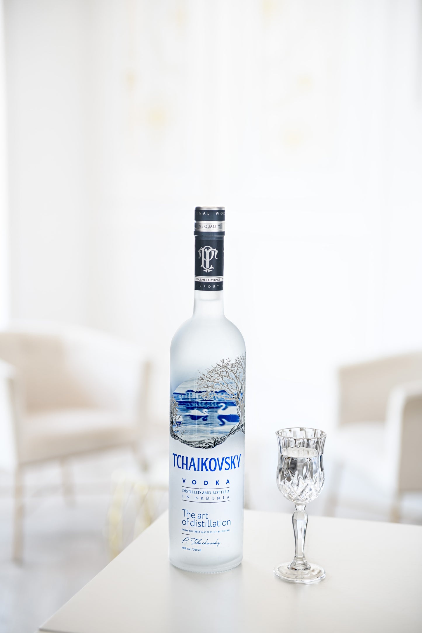Tchaikovsky Vodka bottle next to a crystal shot glass in a bright, elegant room setting.