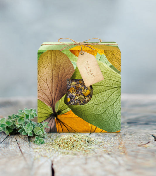 Darman Morning Mood Blend herbal tea in colorful leaf-patterned box with dried herbs on wood