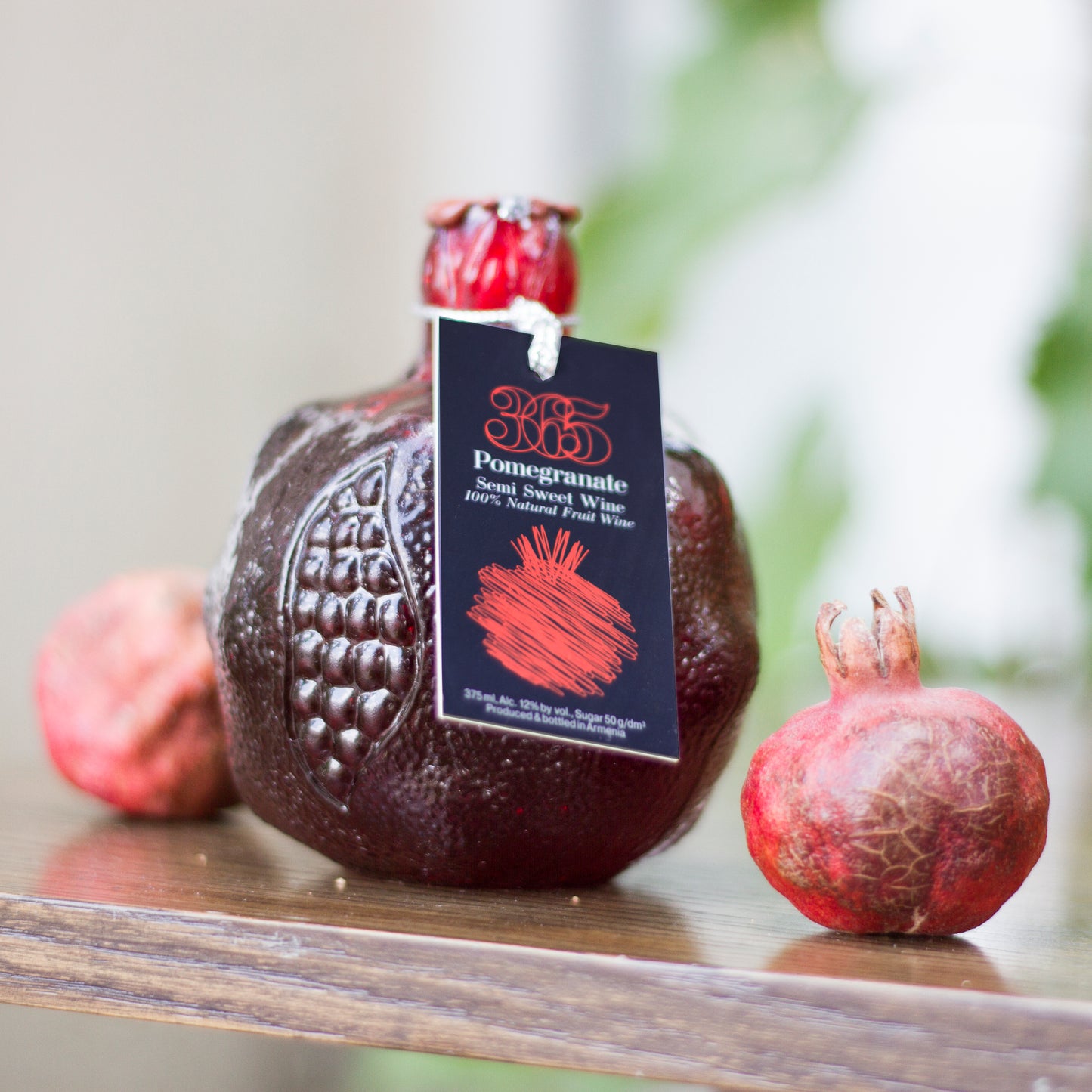 detailed close-up of the souvenir bottle next to fresh pomegranates, highlighting the intricate design.