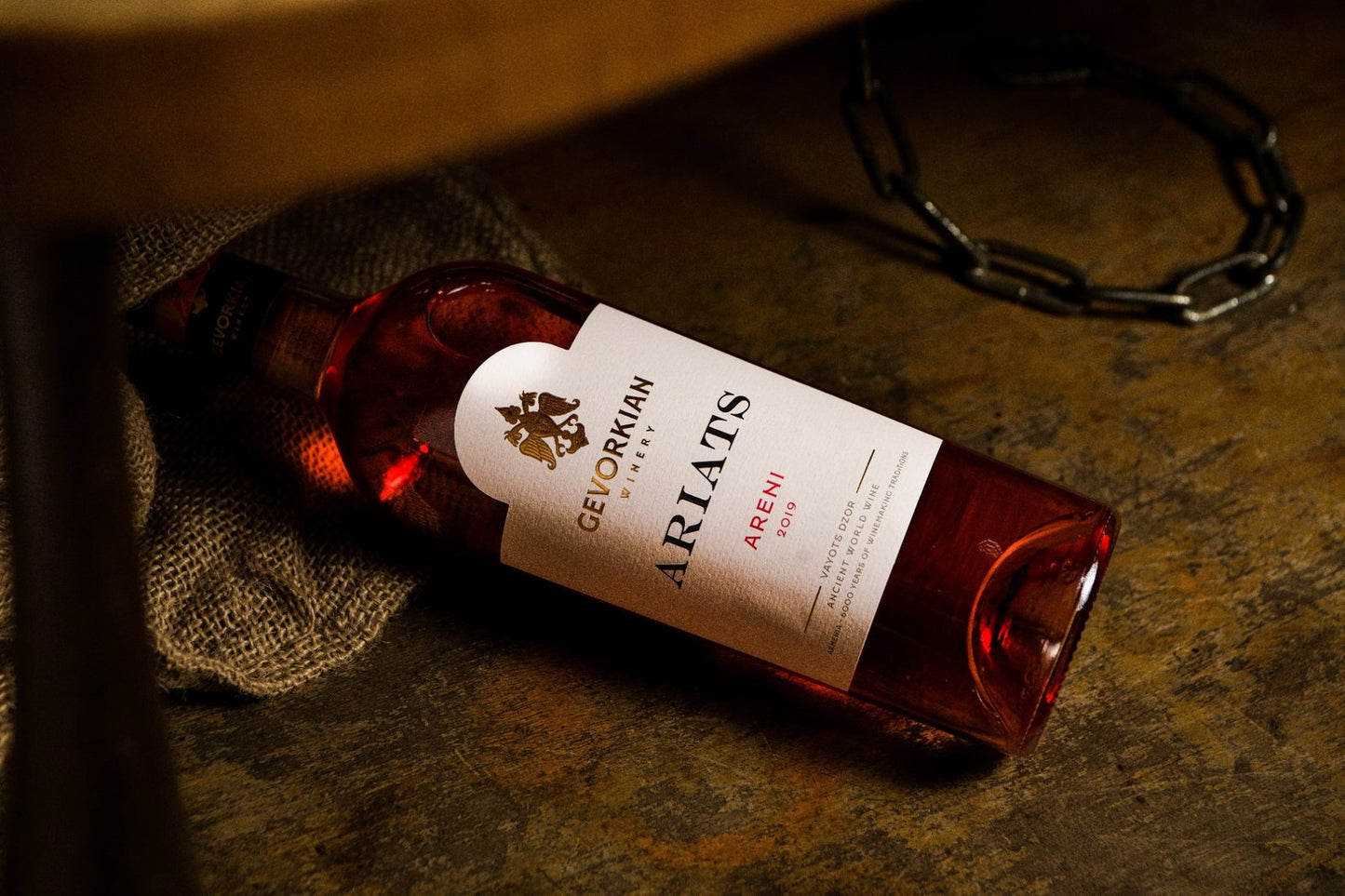 Gevorkian Ariats Areni 2019 rosé wine bottle on rustic surface with burlap and metal chain