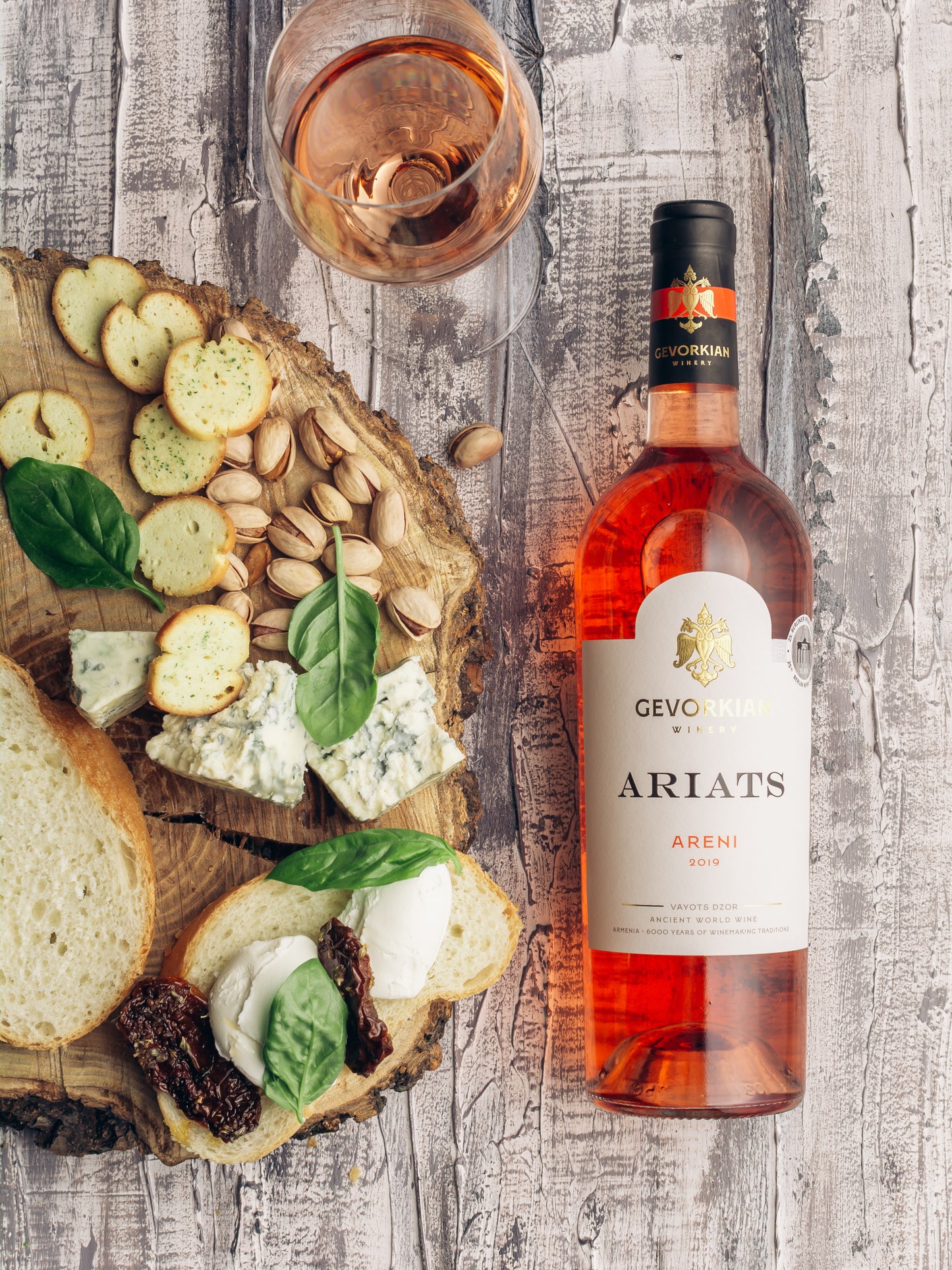 Gevorkian Ariats Areni 2019 rosé wine bottle with cheese board, crackers, and pistachios on rustic wood