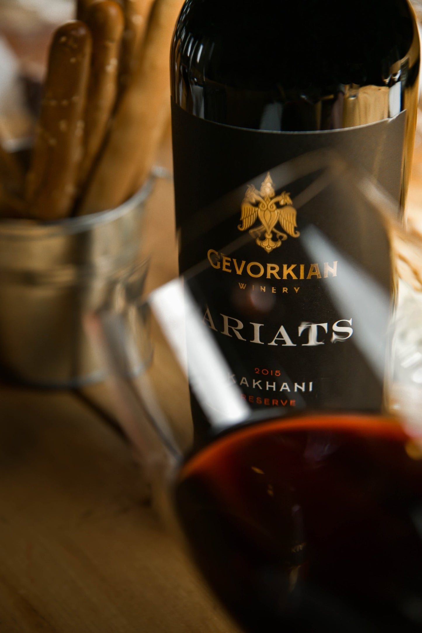 Gevorkian Ariats Kakhani 2015 red wine bottle with blurred red wine glass and breadsticks