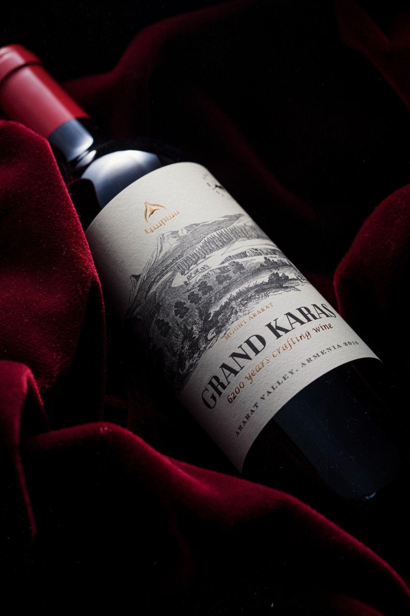 Karas Grand Reserve 2018 bottle on red velvet fabric with gold foil logo and etched Mount Ararat design.
