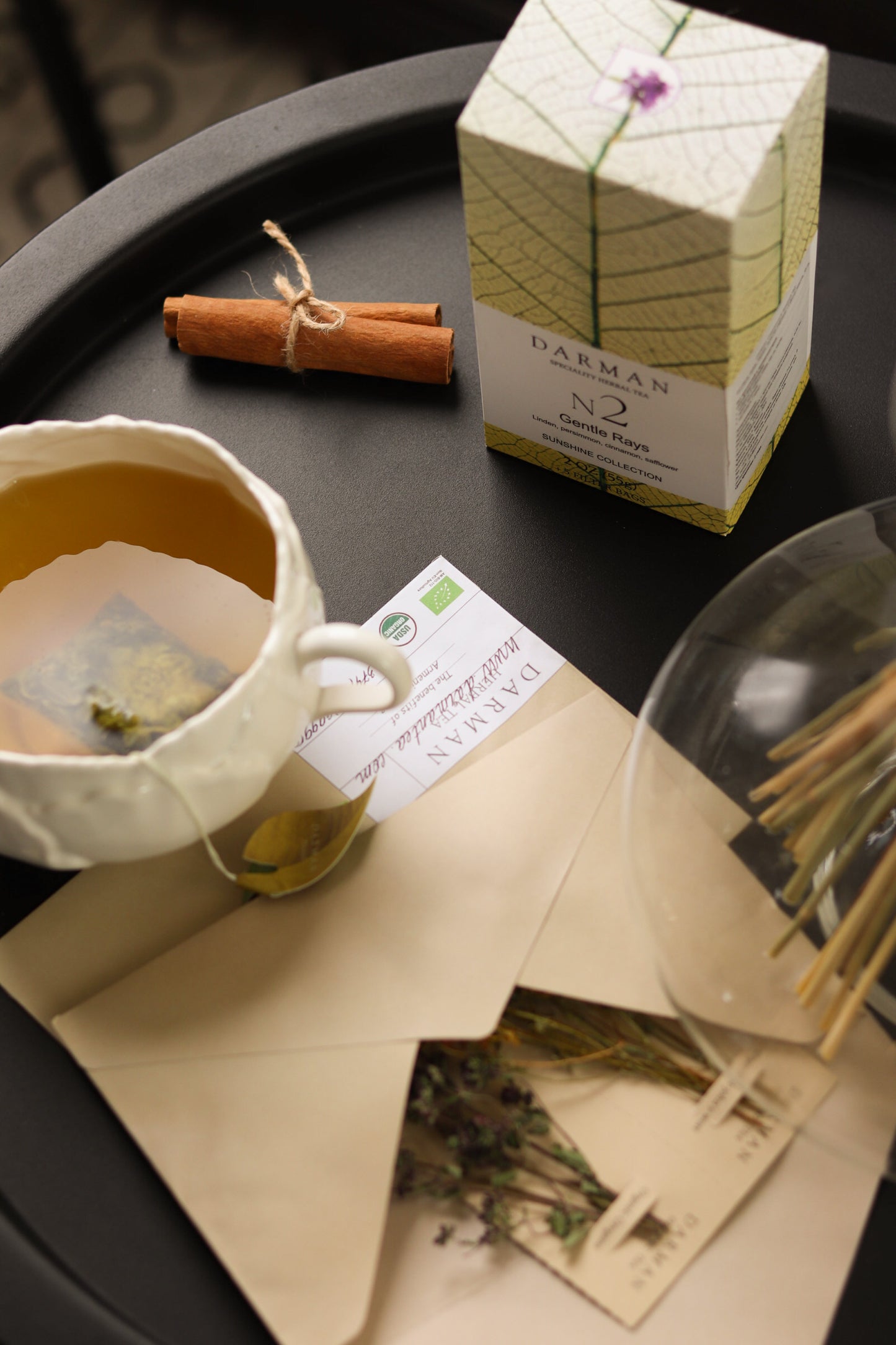 Darman Gentle Rays No.2 tea served in glass pot with box and cinnamon on placemat