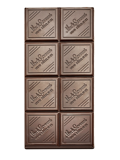 Close-up of the Mark Sevouni 82% Dark Chocolate bar, showing its elegant square segments engraved with the Urban Chocolatier logo.

