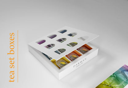 Box lid being lifted to expose individually colored compartments housing Darman’s tea sachets with matching leaf-shaped tags.
