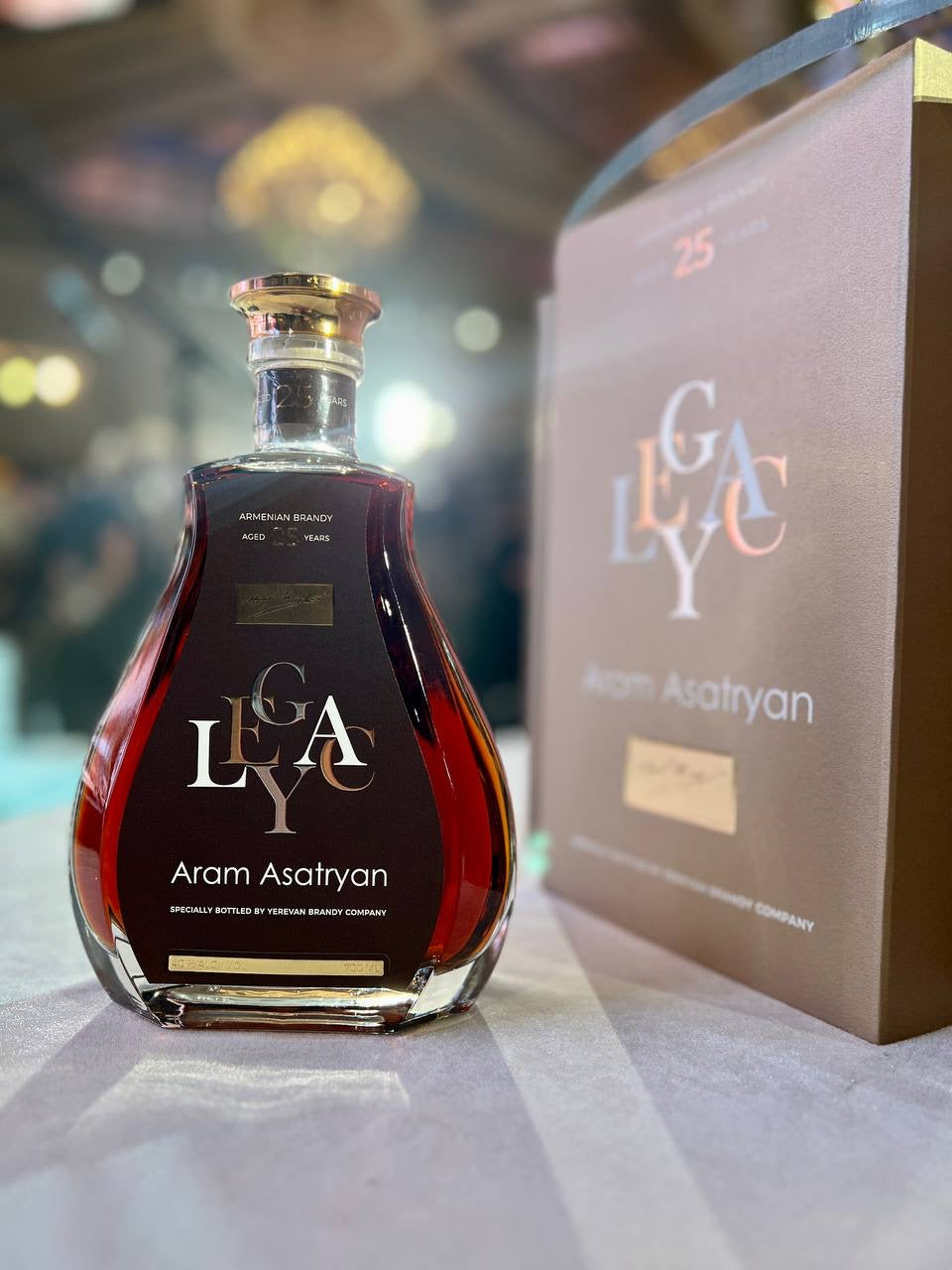 Legacy by Aram Asatryan 25 Year Aged Armenian Brandy in a crystal decanter-style bottle, displayed alongside its elegant gift box at a formal event.