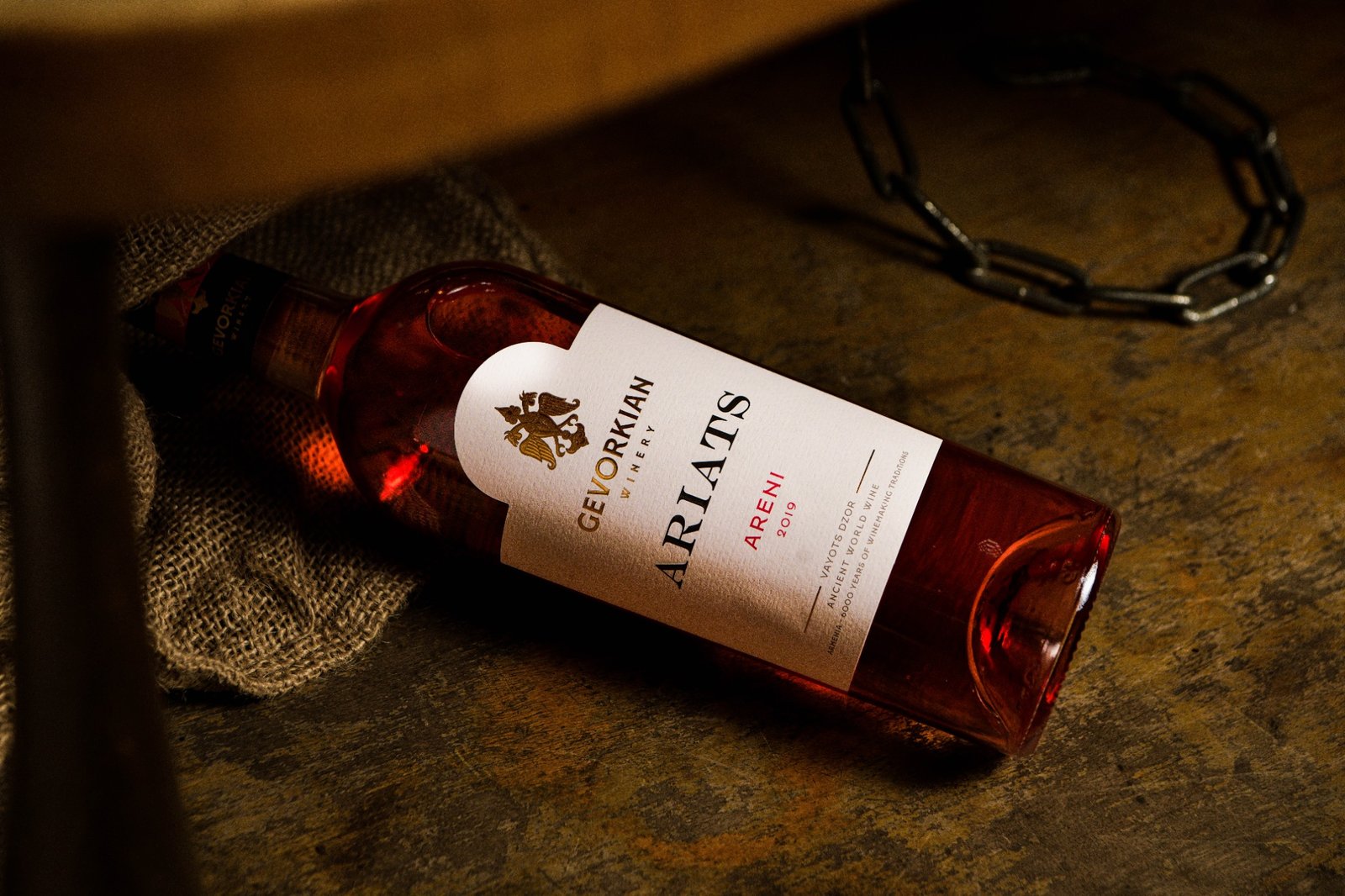 Gevorkian Ariats Areni 2019 rosé wine bottle on rustic surface with burlap and metal chain