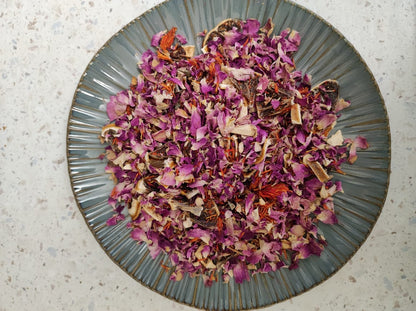 Loose herbal tea blend of Darman N10 Shiny Noon with rose petals and herbs on a ceramic plate